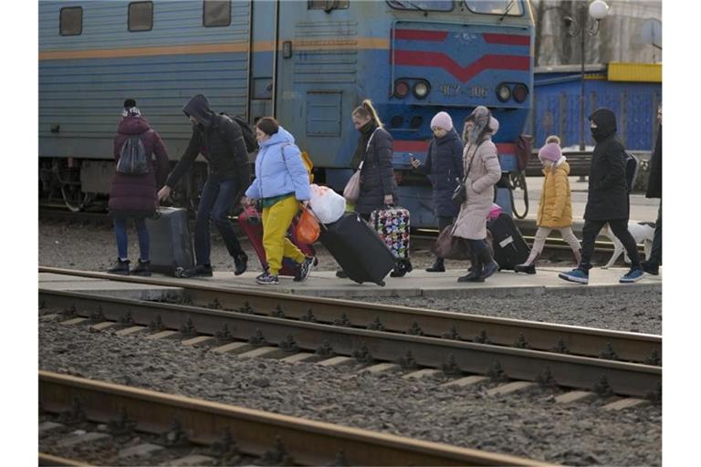 Menschen überqueren mit ihrem Gepäck die Gleise in Kramatorsk in der Region Donezk. Foto: Vadim Ghirda/AP/dpa/Archivbild