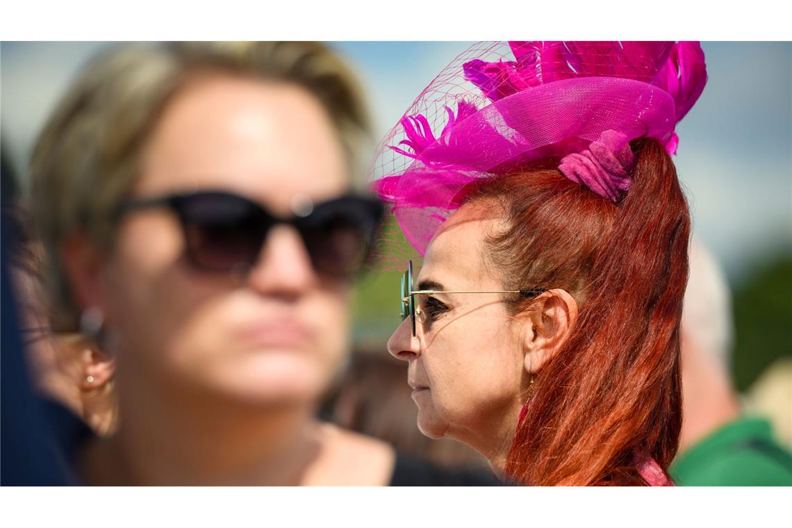 Mit einem pinkfarbenem Hut geht eine Frau über die Galopprennbahn Hamburg Horn beim Idee Derby-Meeting 2024