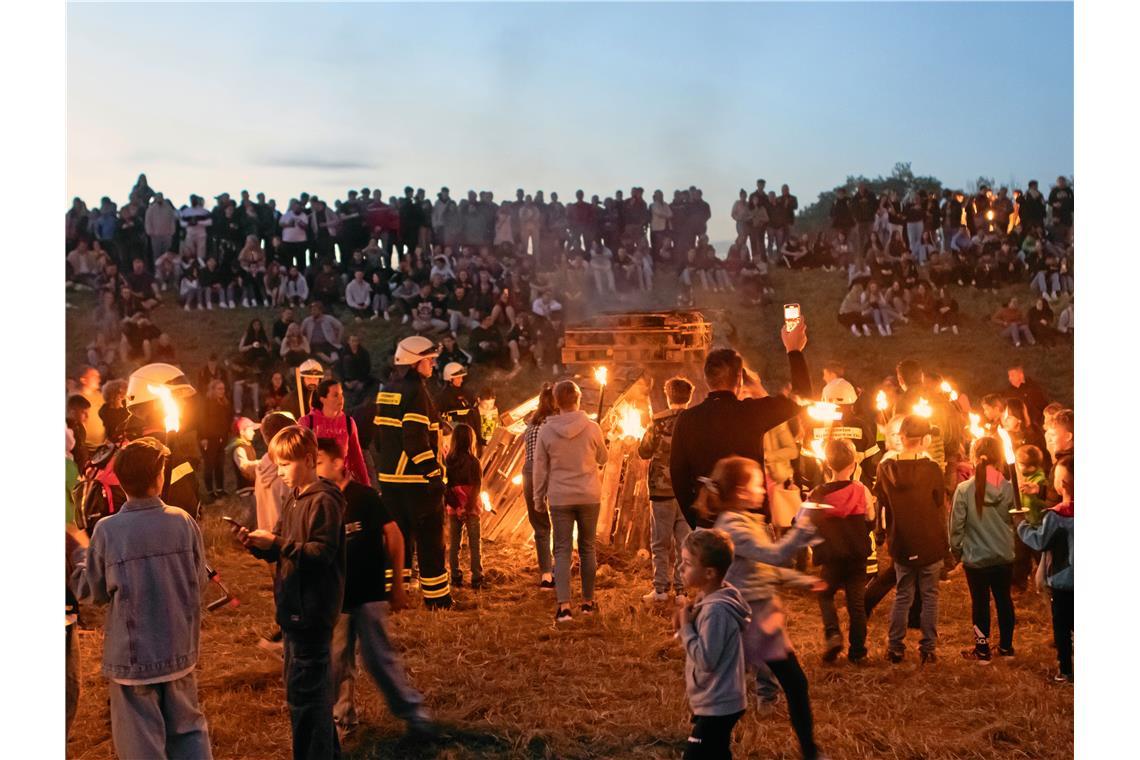 Mit ihren Fackeln entfachen die Gäste das Sonnwendfeuer. Foto: Janina Greco