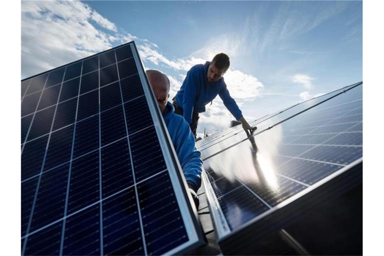 Mitarbeiter der Firma Sontec GmbH montieren Photovoltaikmodule auf dem Dach eines Wohnhauses. Foto: Marijan Murat/dpa/Archivbild