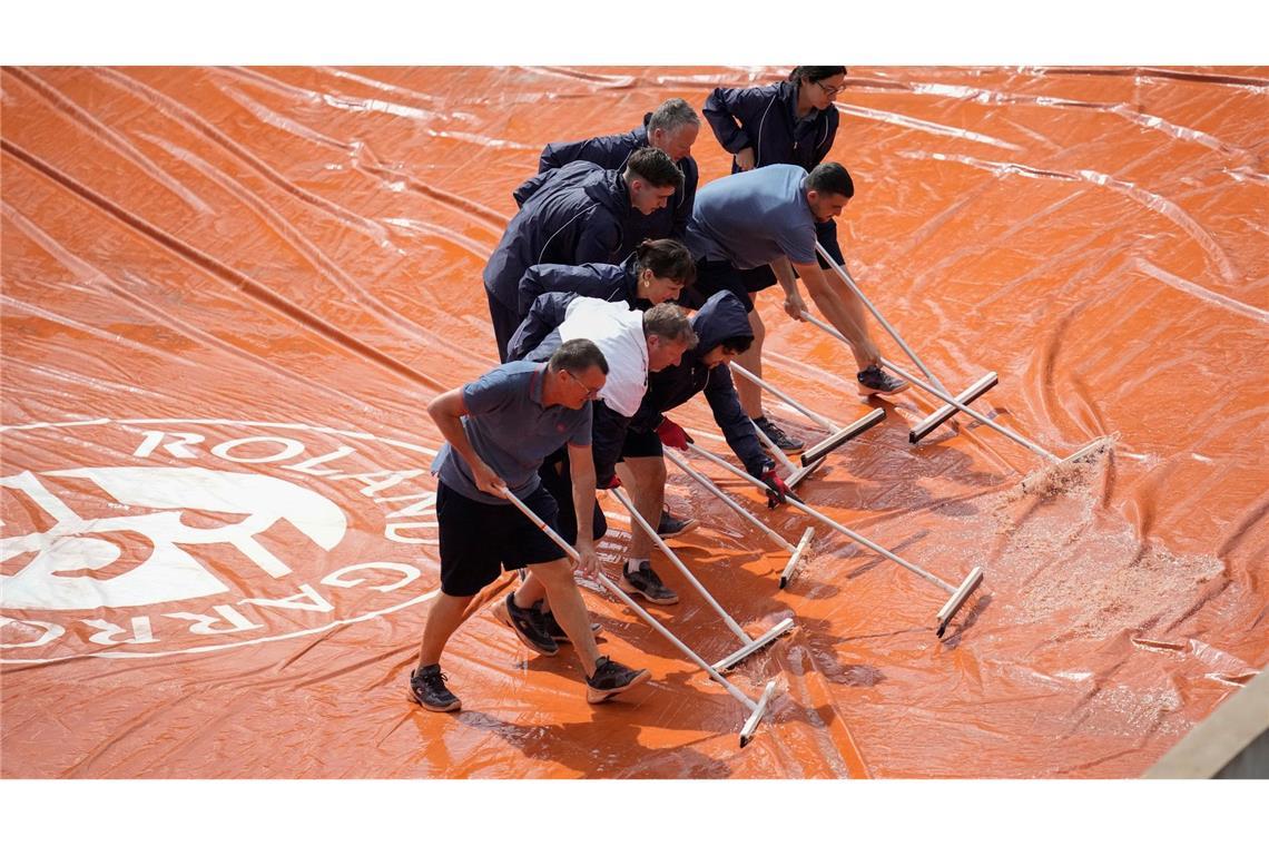 Mitarbeiter der French Open beseitigen Regenwasser von einer Abdeckung. Starke Regenschauer haben bei dem bekannten Tennisturnier in Paris für Unterbrechungen gesorgt.