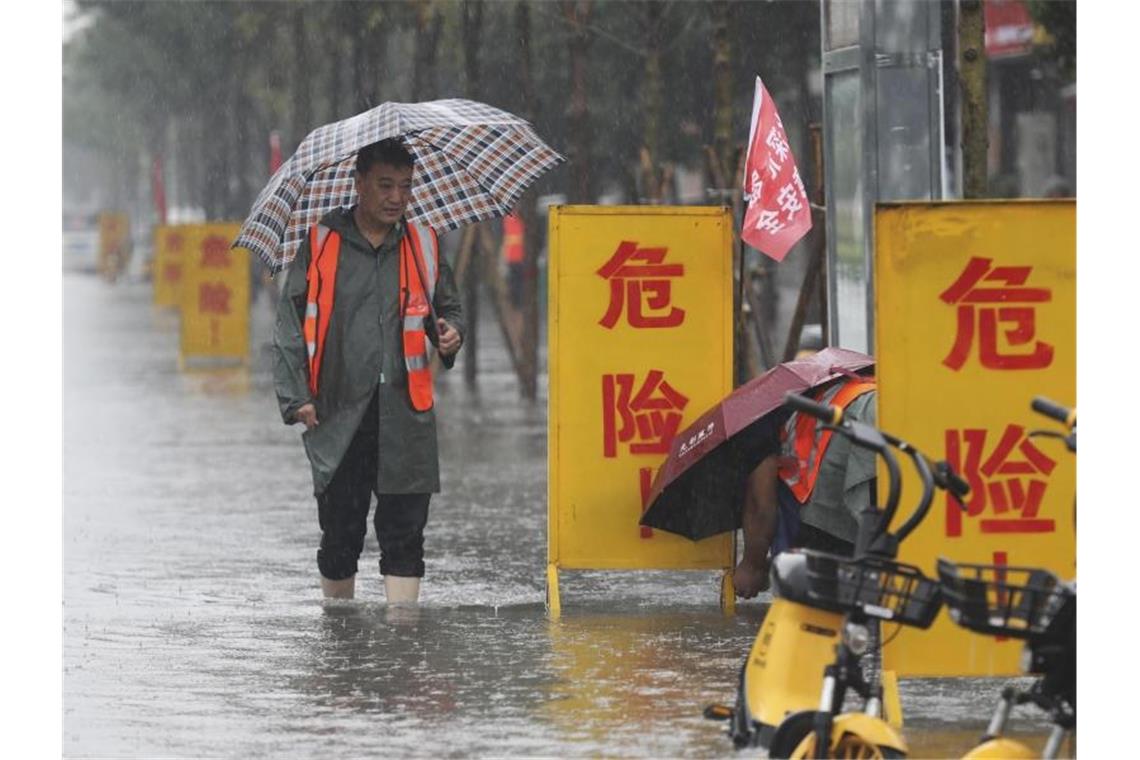 Überschwemmungen stürzen chinesische Metropole ins Chaos Mitarbeiter stellen Warnschilder auf mit der Aufschrift „Gefahr!“ in einem überschwemmten Gebiet im Kreis Wuzhi in der zentralchinesischen Provinz Henan. Foto: Feng Xiaomin/Xinhua/AP/dpa