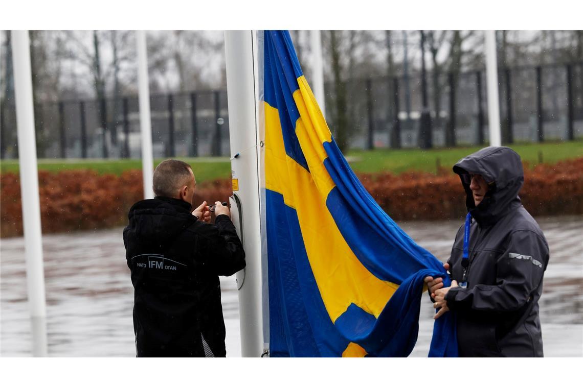 Mitglieder des Protokolls befestigen die schwedische Flagge vor dem Nato-Hauptquartier an einer Fahnenstange. Vier Tage nach dem Beitritt des Landes zum Bündnis wird sie in Brüssel feierlich gehisst.