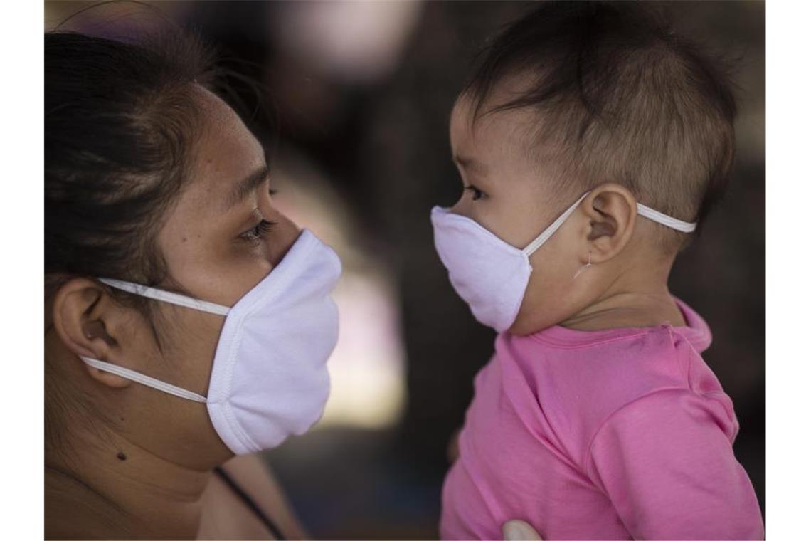 Kinder vermutlich genauso ansteckend wie Erwachsene Mutter und Kind mit Mundschutz: Die Forscher fanden keinen Unterschied in der Viruslast zwischen verschiedenen Altersgruppen. Foto: Rodrigo Abd/AP/dpa/Symbolbild