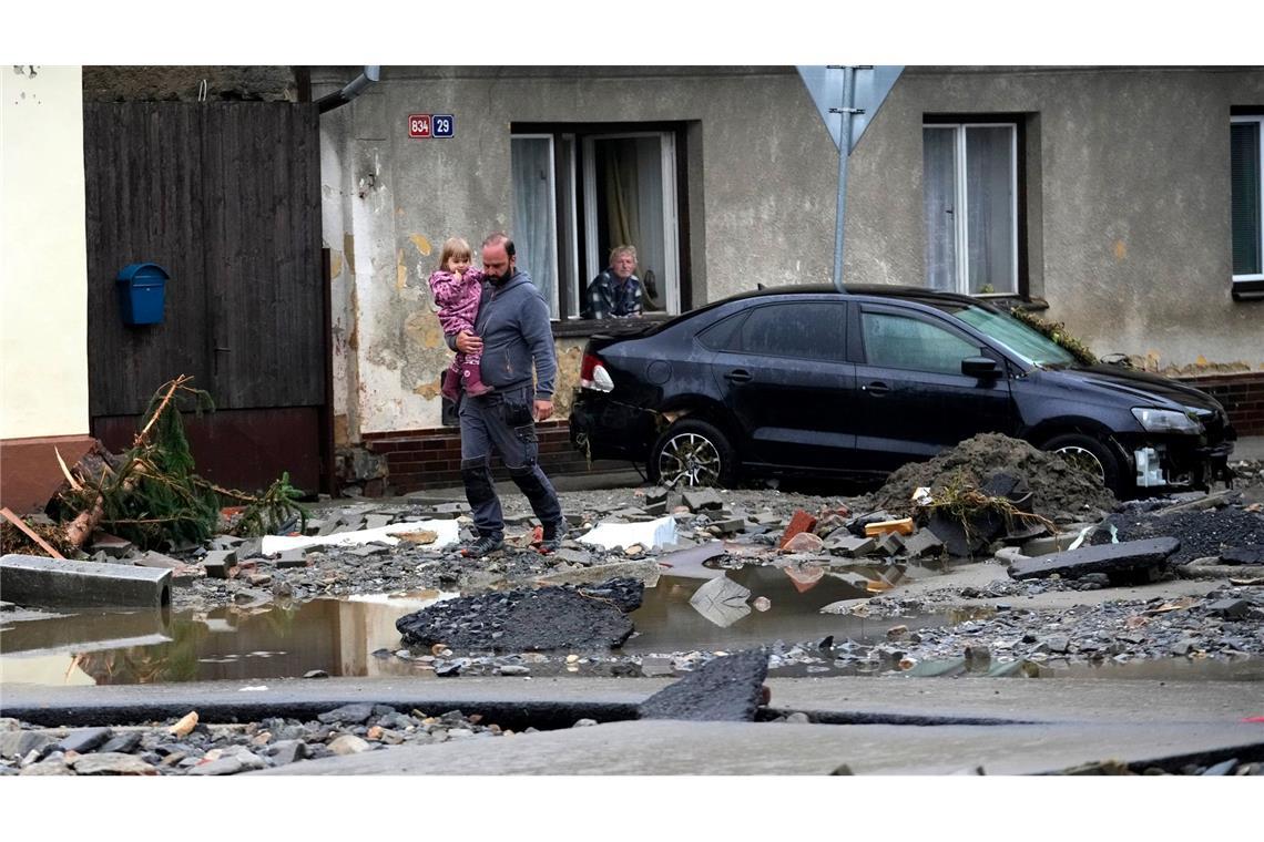 Nach den verheerenden Überschwemmungen in Tschechien laufen die Anwohner durch die zerstörte Straße