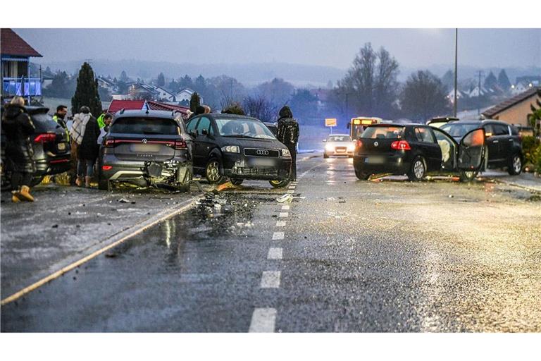 Nach einem Unfall bei Glatteis mit mehreren Fahrzeugen in Baden-Württemberg stehen Helfer und Beteiligte an den Autos auf einer Straße.