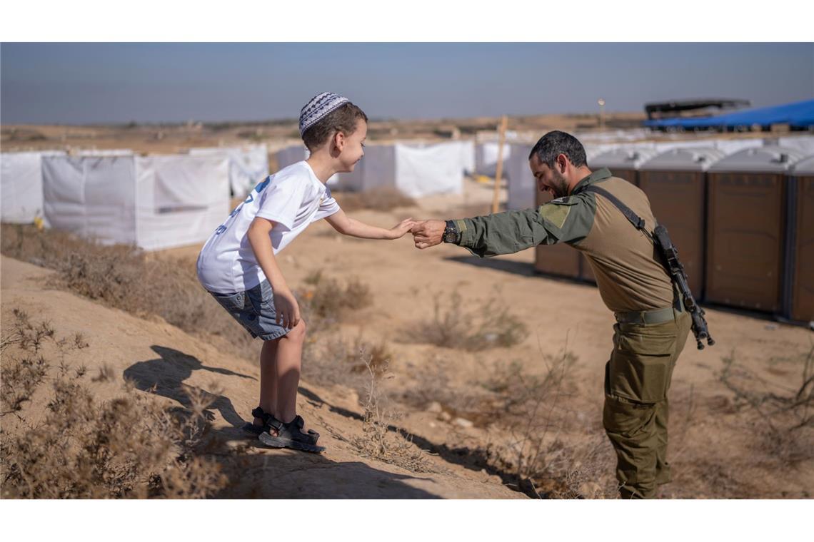 Nahostkonflikt - Kibbuz Be'eri: Ein israelischer Soldat hilft einem Kind beim Abstieg von einem Hügel während einer Veranstaltung im Rahmen des Laubhüttenfestes oder Sukkot-Festes.