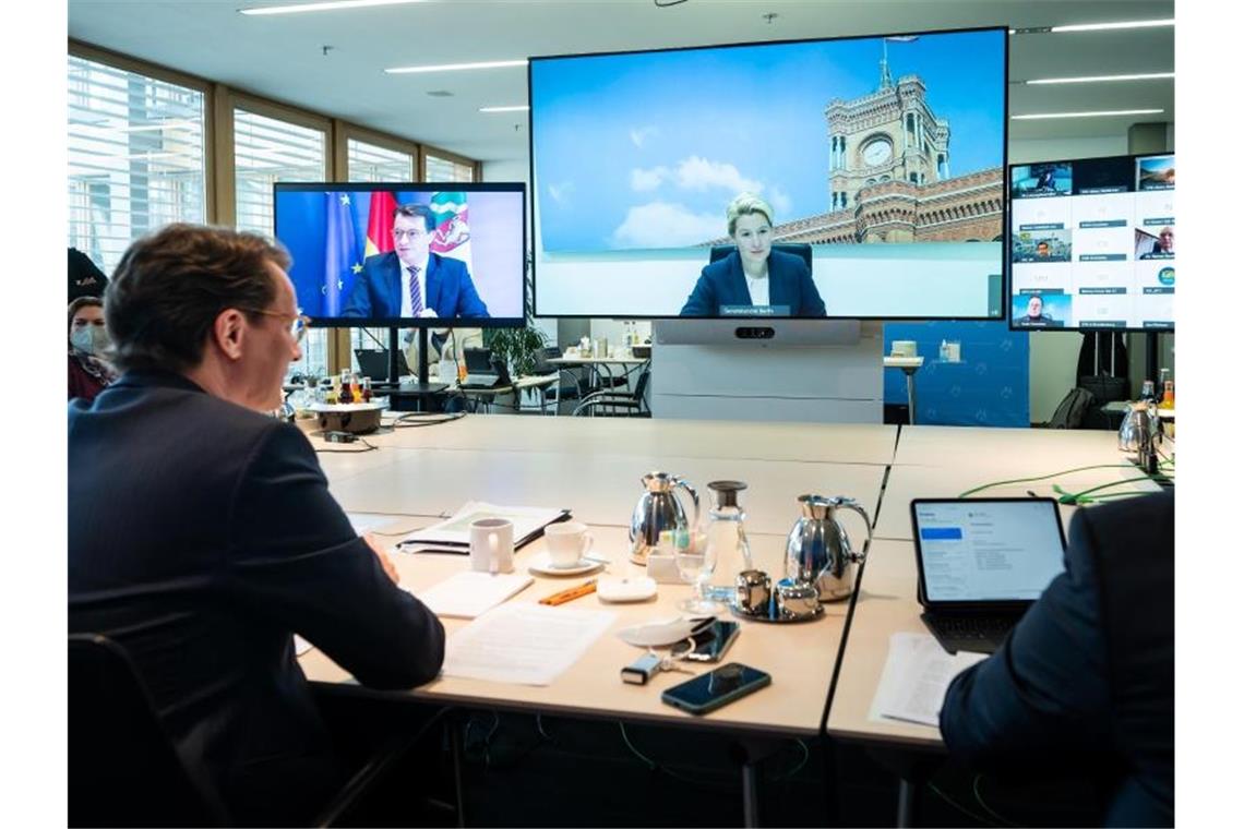 Corona-Gipfel: 2G plus für Restaurants und Kneipen NRW-Ministerpräsident Hendrik Wüst (l.), während der Videokonferenz. Auf dem großen Bildschirm ist Berlins Regierende Bürgermeisterin Franziska zugeschaltet. Foto: Bernd von Jutrczenka/dpa