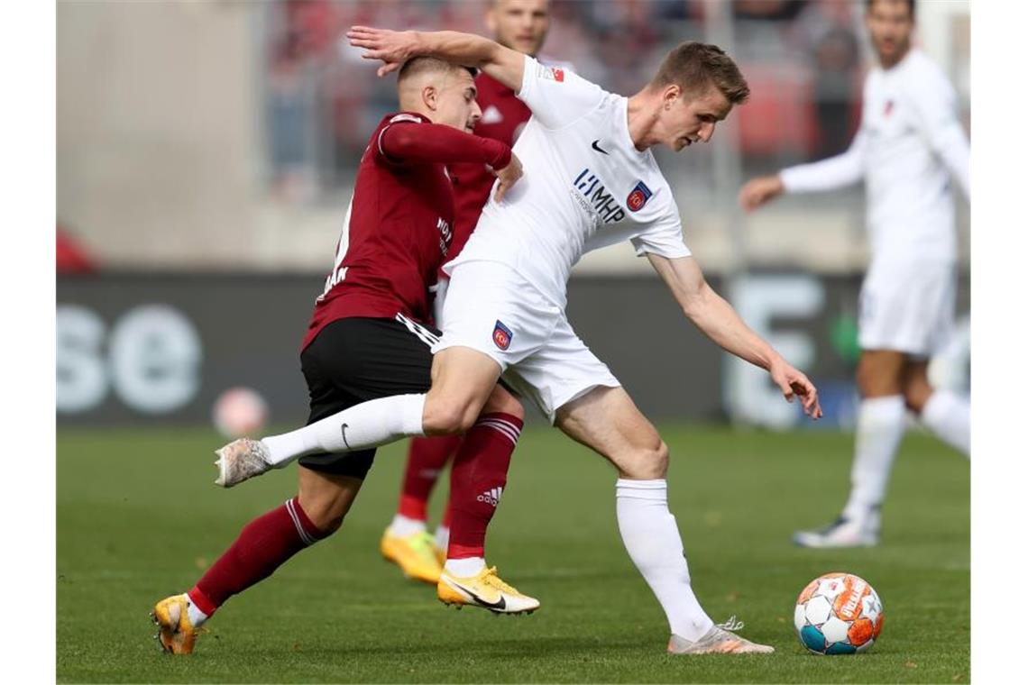 Nürnbergs Nikola Dovedan (l) kämpft mit Heidenheims Jan Schöppner um den Ball. Foto: Daniel Karmann/dpa