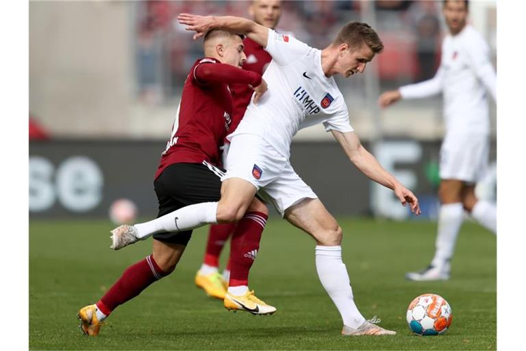 Nürnbergs Nikola Dovedan (l) kämpft mit Heidenheims Jan Schöppner um den Ball. Foto: Daniel Karmann/dpa