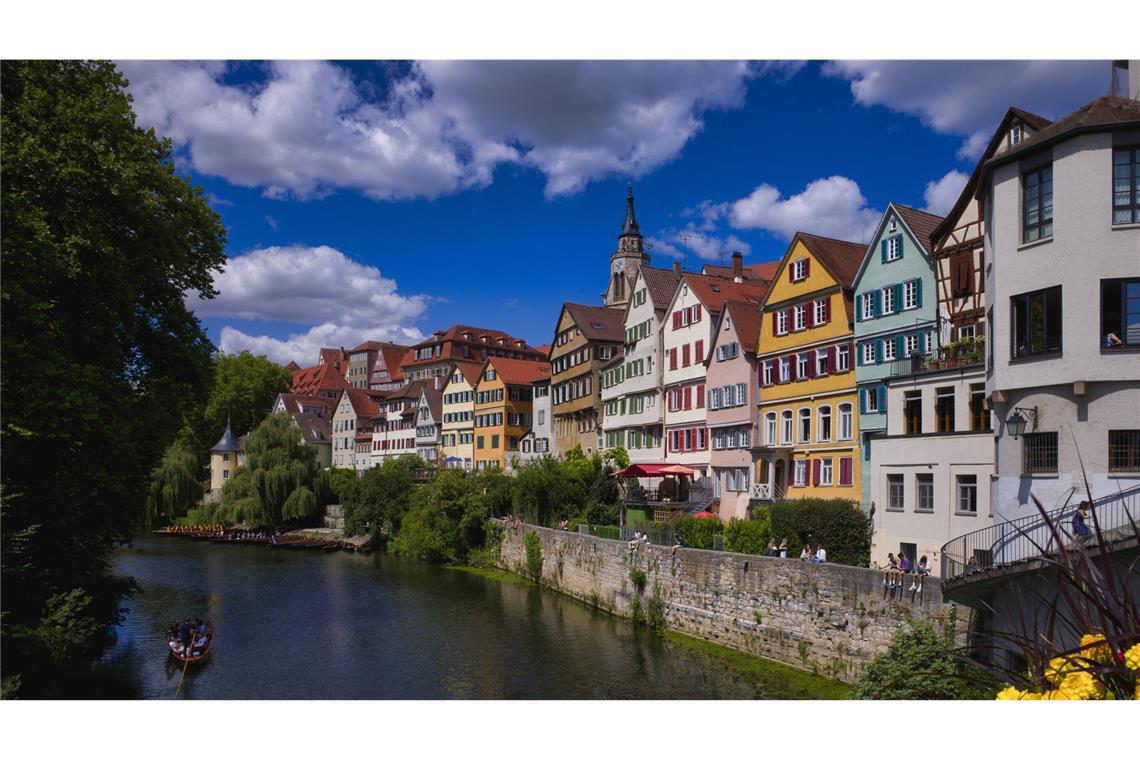 Oft sind ganze Häuserzeilen und Viertel denkmalschutzwürdig, weil sie auch das Stadtbild prägen und von der Geschichte des Ortes erzählen. Blick über Neckar auf die Altstadt, Stocherkähne, die Stiftskirche St. Georg in Tübingen.