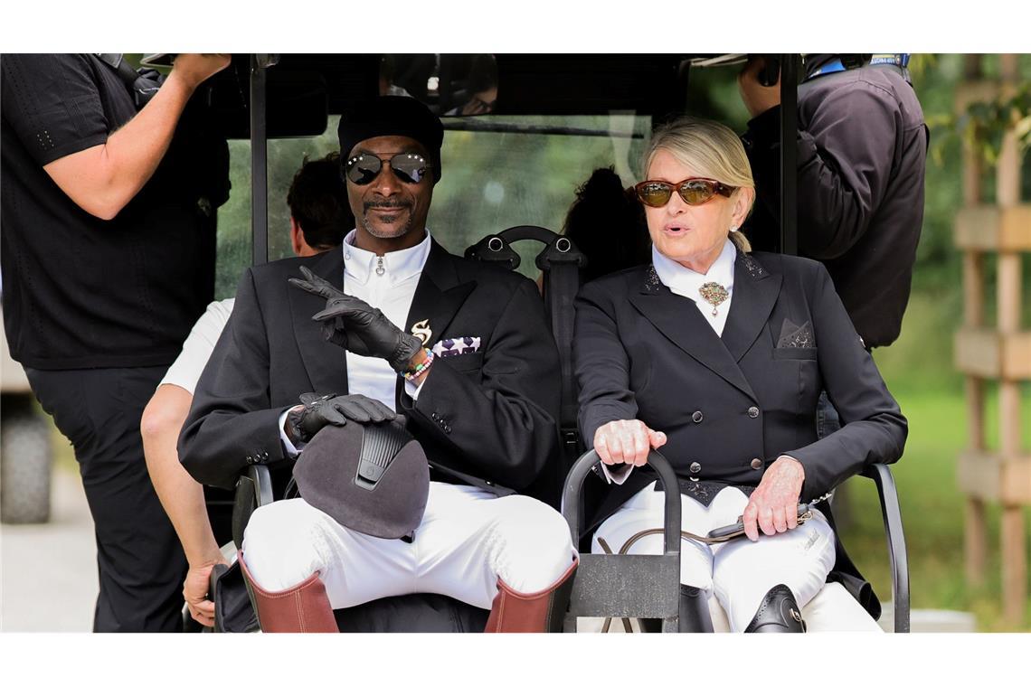 Olympia-Edelfans beim Dressur-Finale: Hiphop-Star Snoop Dogg (l) und die US-amerikanische Fernsehmoderatorin Martha Stewart sitzen in Reitkleidung nebeneinander in einem Golfcart in Versailles.