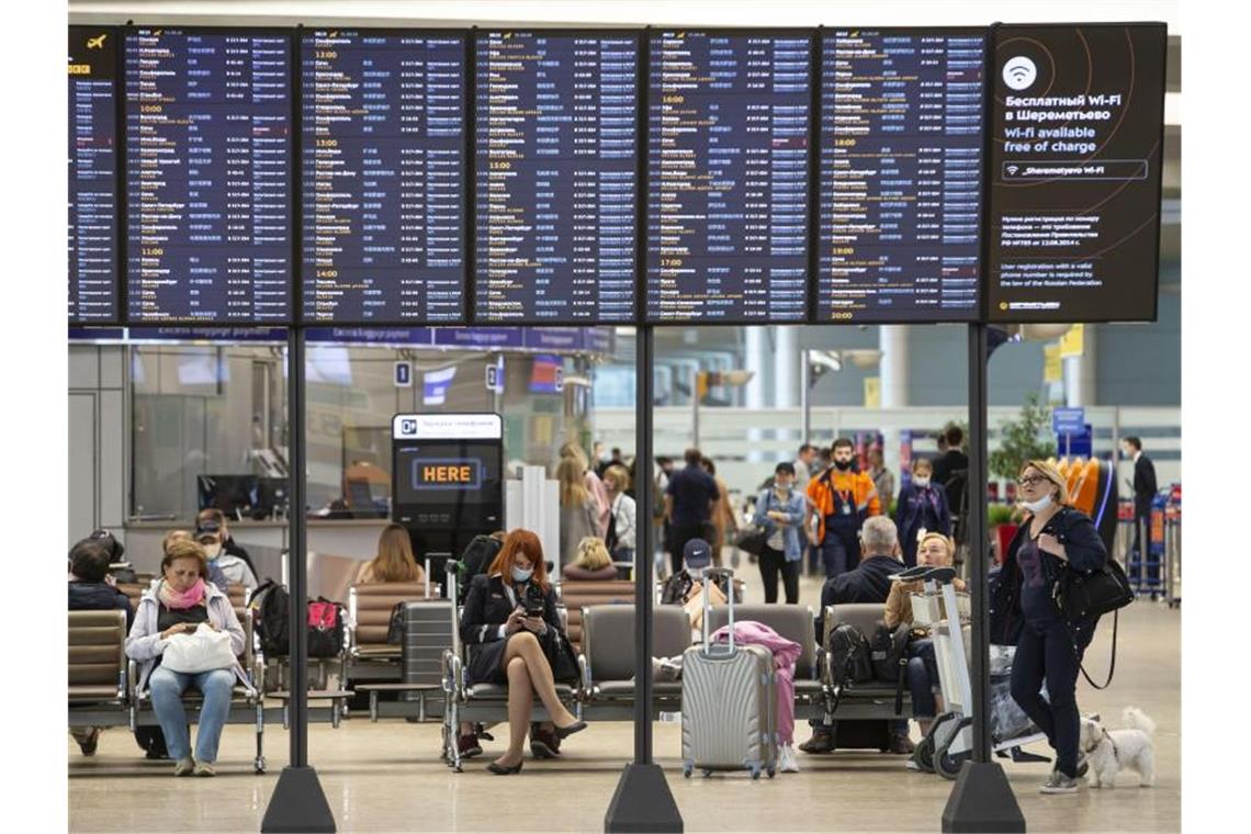 Russland nimmt Flugverkehr mit acht Ländern wieder auf Passagiere sitzen auf dem internationalen Flughafen Scheremetjewo in Moskau unter einer Fluginformationstafel. Russland nimmt trotz der Corona-Pandemie den regulären Flugverkehr mit acht Ländern wieder auf. Foto: Alexander Zemlianichenko Jr/XinHua/dpa