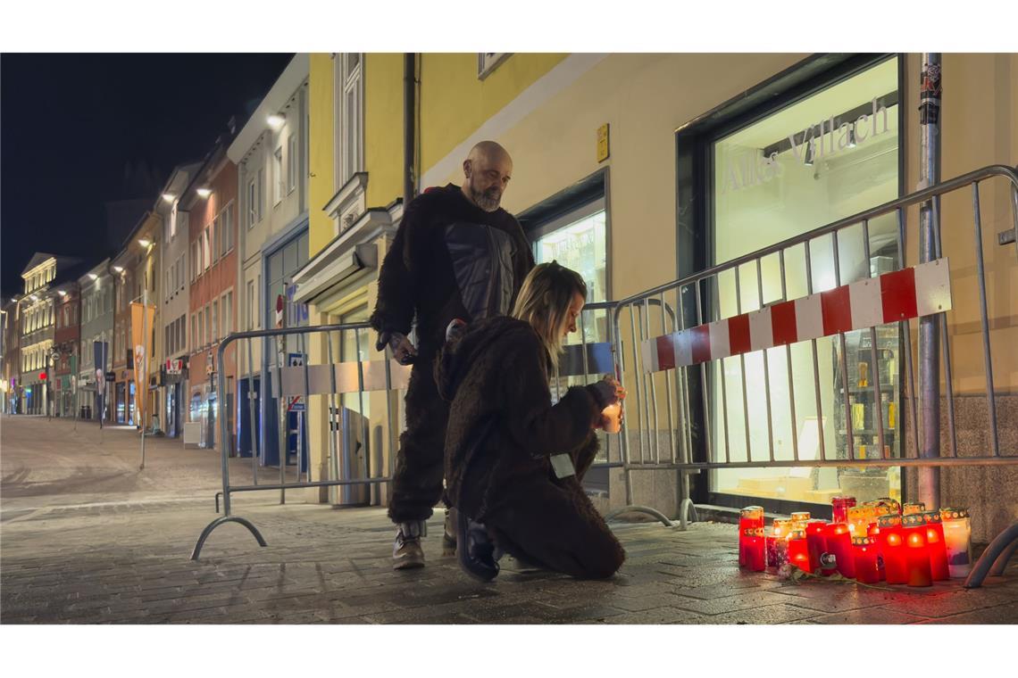 Passanten zünden Kerzen am Ort des Messerangriffs in Villach an.