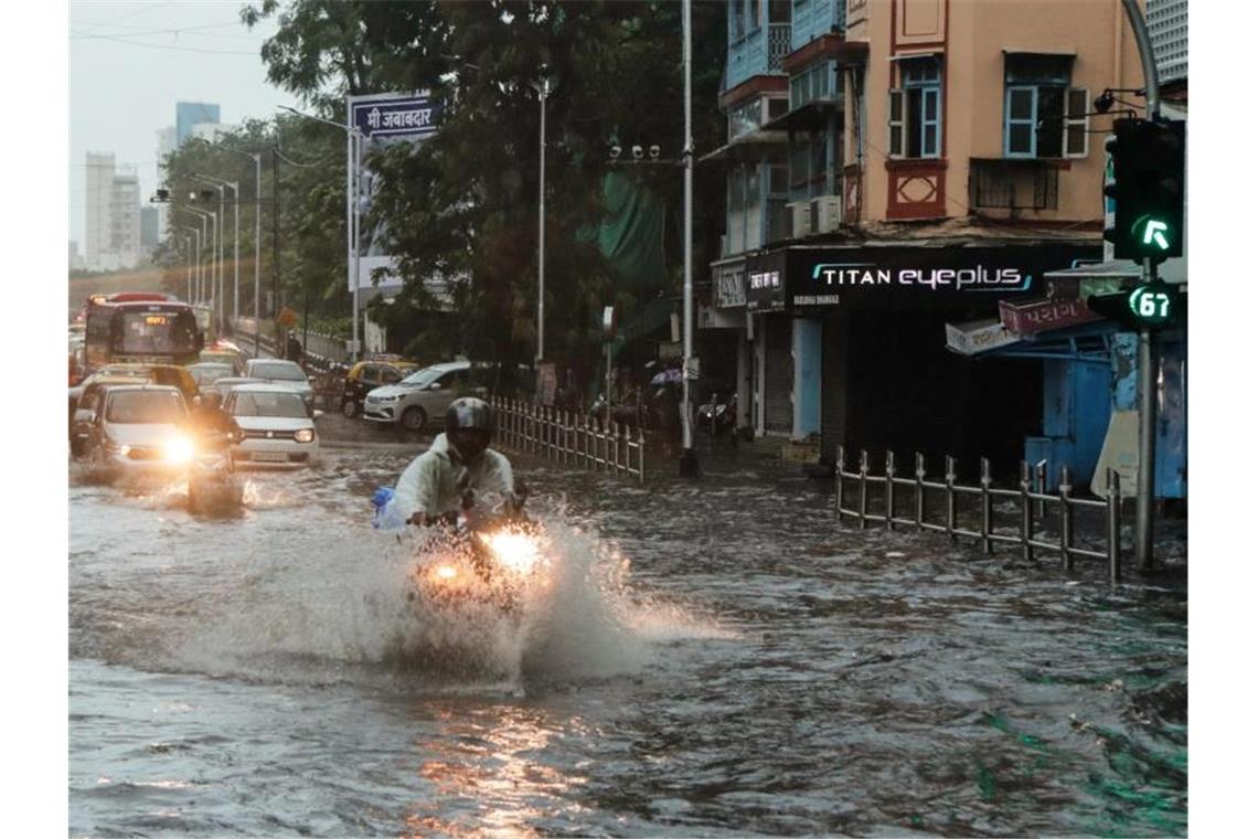 Indische Marine: Lastkahn sinkt bei Zyklon Pendler fahren in Mumbai auf einer überschwemmten Straße. Foto: Rajanish Kakade/AP/dpa