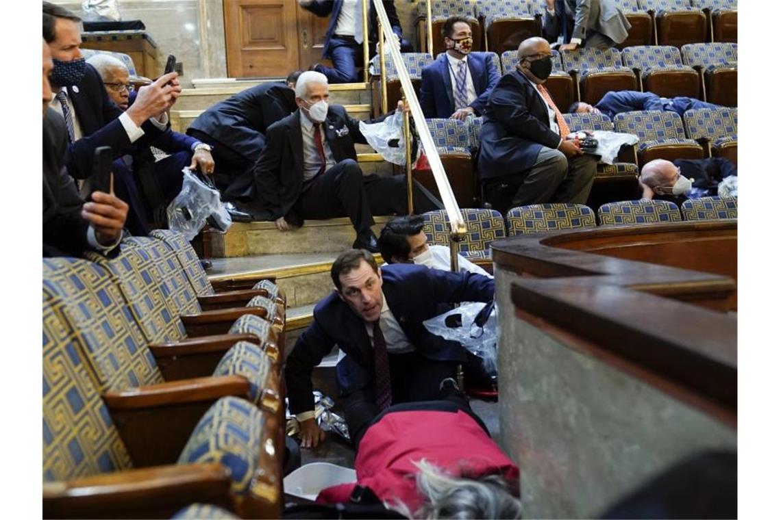 Kapitol-Jahrestag: Biden macht Trump verantwortlich Politiker suchen Schutz in der Galerie des Repräsentantenhauses, als Randalierer versuchen, während Trump-Anhänger in das Parlament eindringen. Foto: Andrew Harnik/AP/dpa