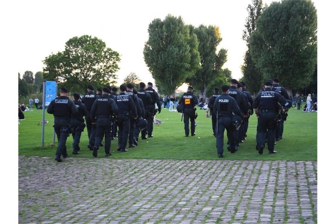 Polizeibeamte gehen über die Neckarwiese. Foto: Rene Priebe/dpa/Archivbild