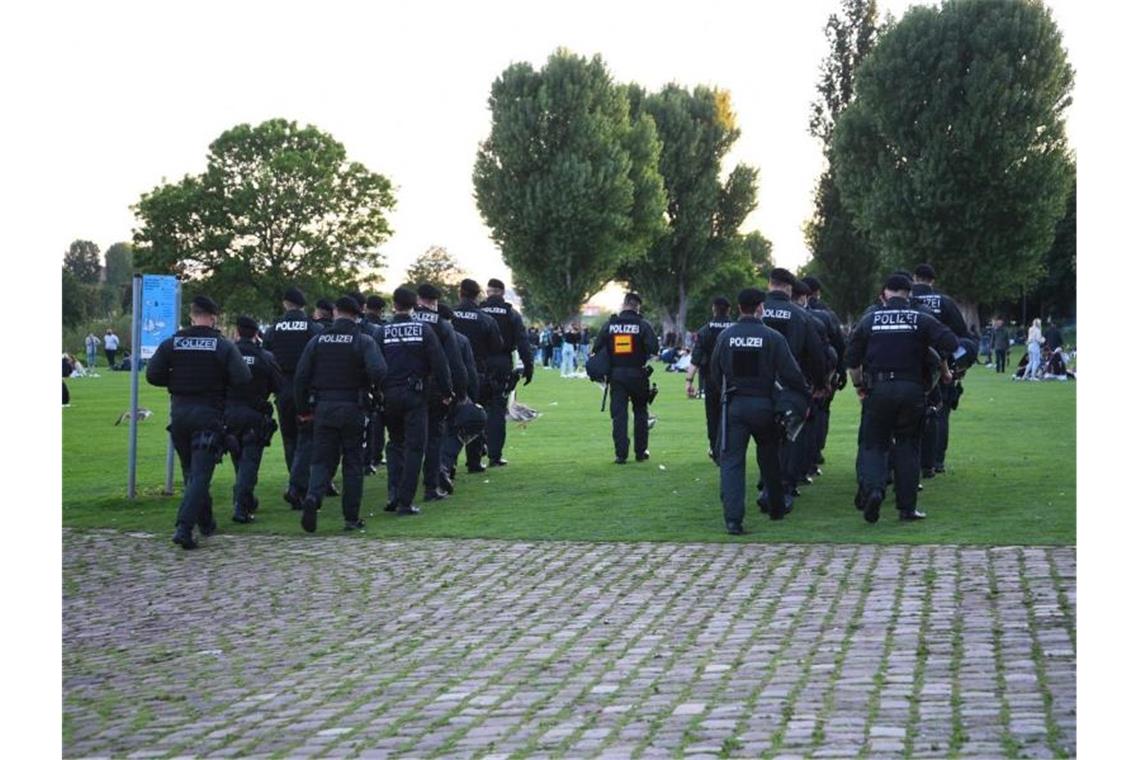 Polizeibeamte gehen über die Neckarwiese. Foto: Rene Priebe/dpa/Archivbild