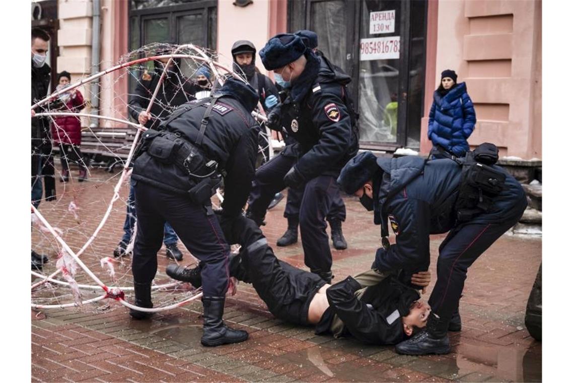 Nawalny und die Putin-Proteste - EU berät neue Sanktionen Polizeibeamte ziehen den Oppositionsaktivisten Pawel Krysewitsch aus einer Stacheldrahtkugel. Foto: George Markov/AP/dpa