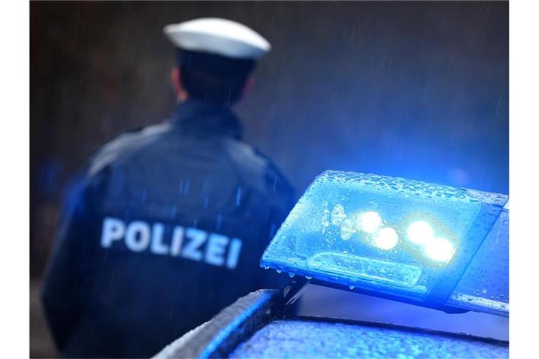 Polizist neben einem Streifenwagen. Foto: Karl-Josef Hildenbrand/dpa/Archivbild