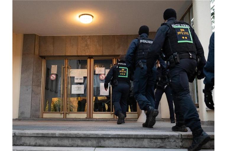 Polizisten betreten auf dem Gelände der Heidelberger Universität das Gebäude, in dem sich Amoklauf ereignete. Foto: Sebastian Gollnow/dpa