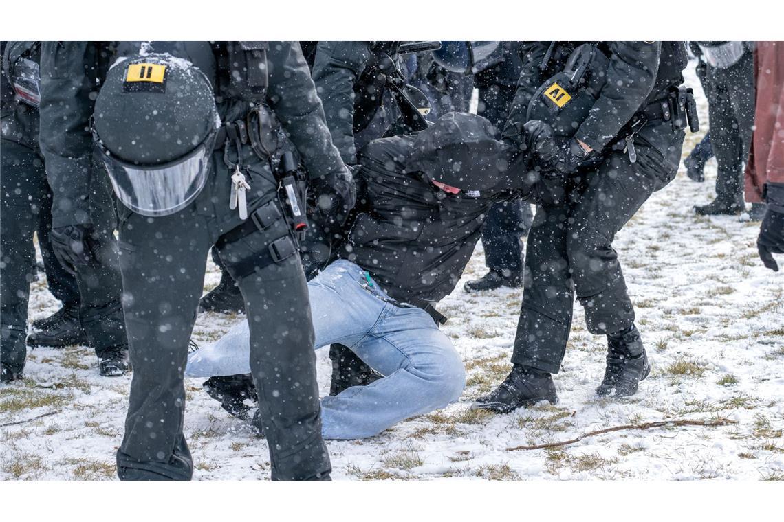 Polizisten bringen am Rande einer Demonstration eine Person zu Boden.