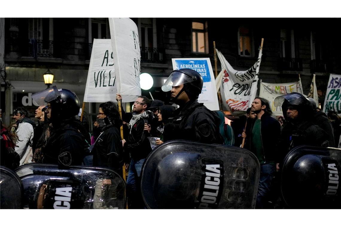 Polizisten gehen neben Demonstranten, die gegen die Politik des argentinischen Präsidenten Milei protestieren.