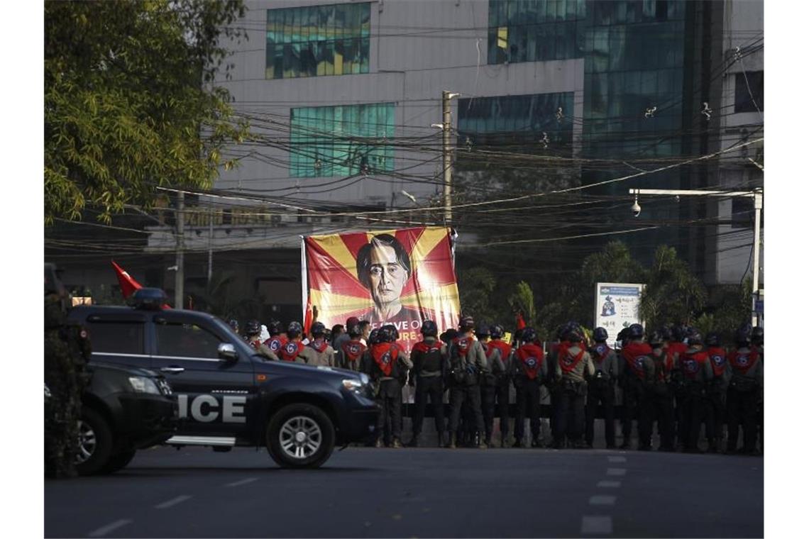 Protest gegen Junta in Myanmar reißt nicht ab Polizisten stehen in Rangun vor Teilnehmern eines Protestes gegen den jüngsten Militärputsch. Auf einem großen Transparent: das Bild der Regierungschefin Suu Kyi. Foto: Uncredited/AP/dpa