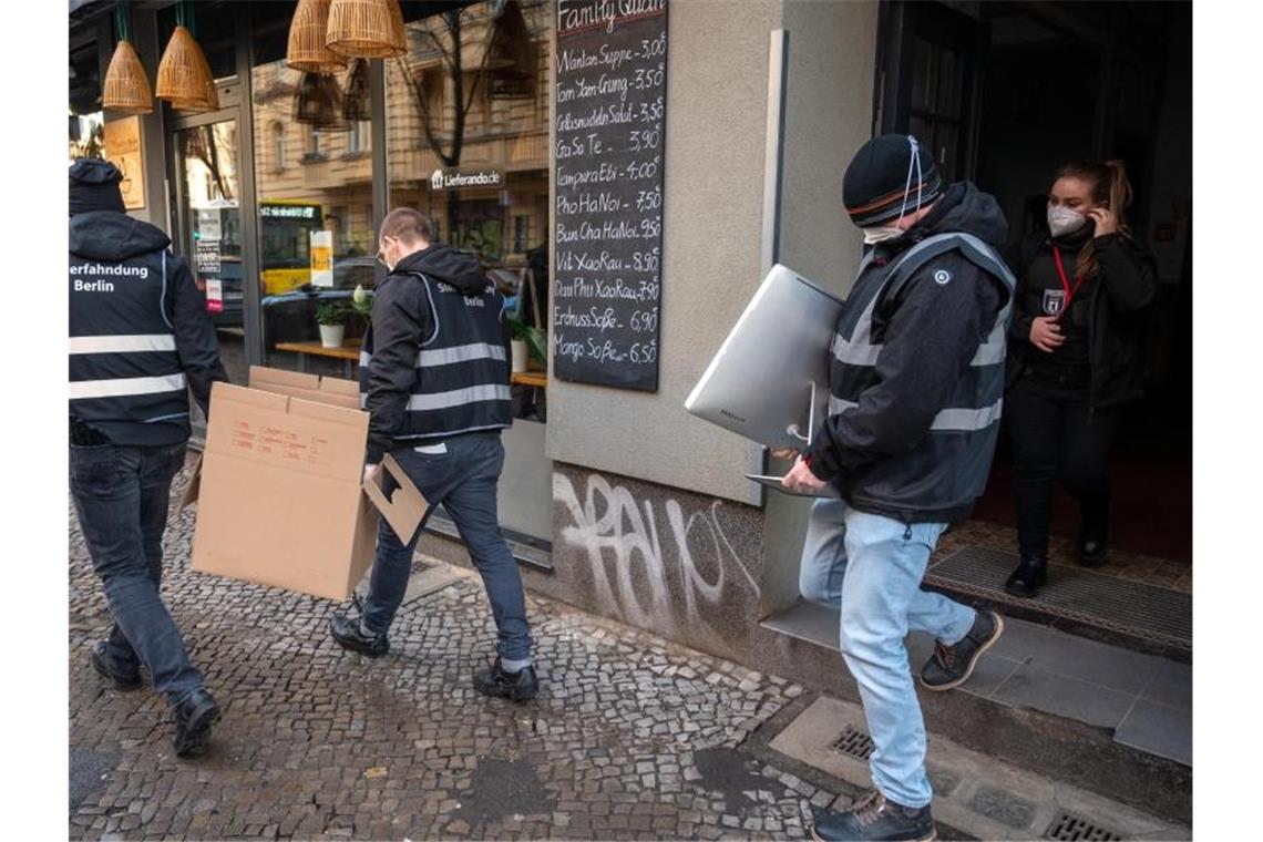 Kriminellen-Chats geknackt - Schlag gegen Clan-Kriminelle Polizisten tragen bei einer Razzia in Berlin Neukölln eine Kiste und einen Computer aus einem Haus. Foto: Christophe Gateau/dpa