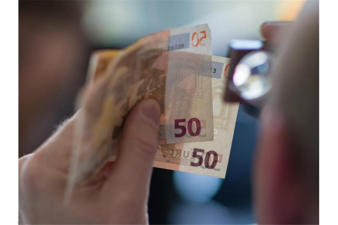Pandemie setzt Geldfälschern zu: Deutlich weniger Falschgeld Prüfender Blick: Wegen den Corona-Einschränkungen ist weniger Falschgeld im Umlauf. Foto: Andreas Arnold/dpa/Illustration