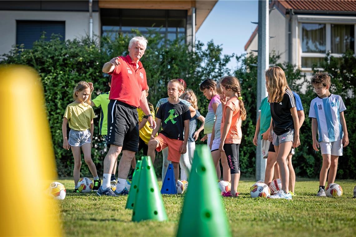 Rainer Dietrich erklärt den aufmerksamen Drittklässlern aus Großerlach, wie sie erst dribbeln und dann abziehen sollen. Foto: Alexander Becher