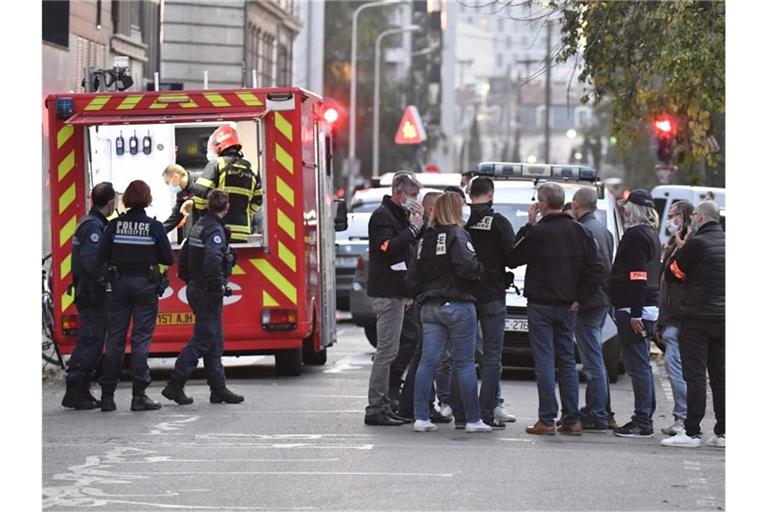 Rettungskräfte und Beamte der Polizei stehen am Tatort, an dem ein griechisch-orthodoxer Priester angeschossen wurde. Foto: Philippe Desmazes/AFP/dpa