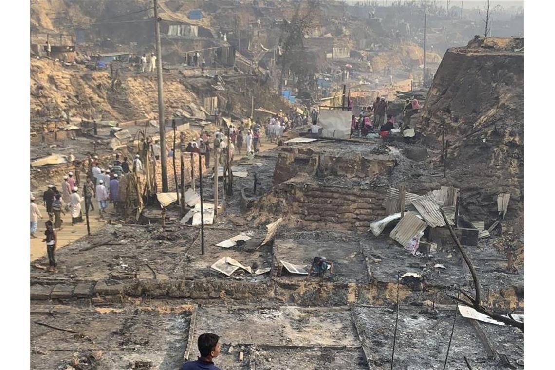 Bangladesch: Tote bei Brand in Flüchtlingslager für Rohingya Rohingya-Geflüchtete betrachten nach dem Brand die Überreste des Flüchtlingslager. Foto: Shafiqur Rahman/AP/dpa