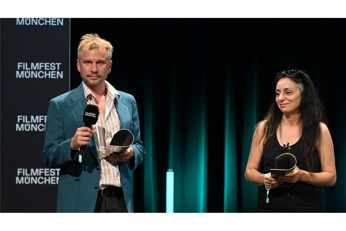 Schauspieler Robert Stadlober steht mit seinem Publikumspreis für den Film "Führer und Verführer" neben der Regisseurin Yasemin Samdereli, die für den Film "Samia" bei der Preisverleihung im Rahmen des Filmfest München ausgezeichnet wurde.