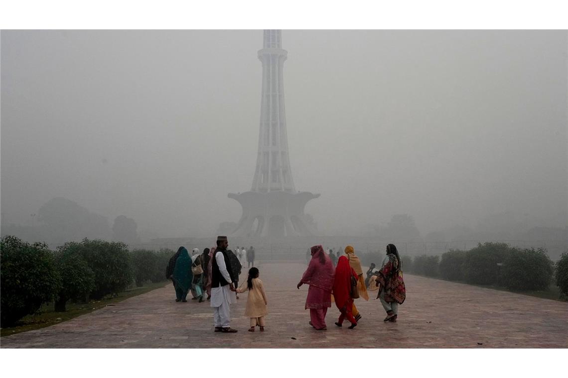 Schlechte Luft: Familien gehen vor dem Pakistan-Denkmal in Lahore in Pakistan entlang, während Smog die Stadt in eine graue Dunstglocke einhüllt.