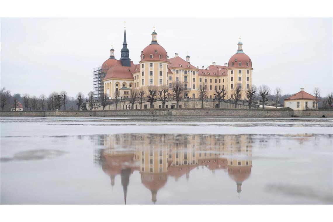 Schloss gespiegelt: Das Schloss Moritzburg in Sachsen spiegelt sich im Tauwassser auf in einer Eisfläche auf dem Schlossteich.