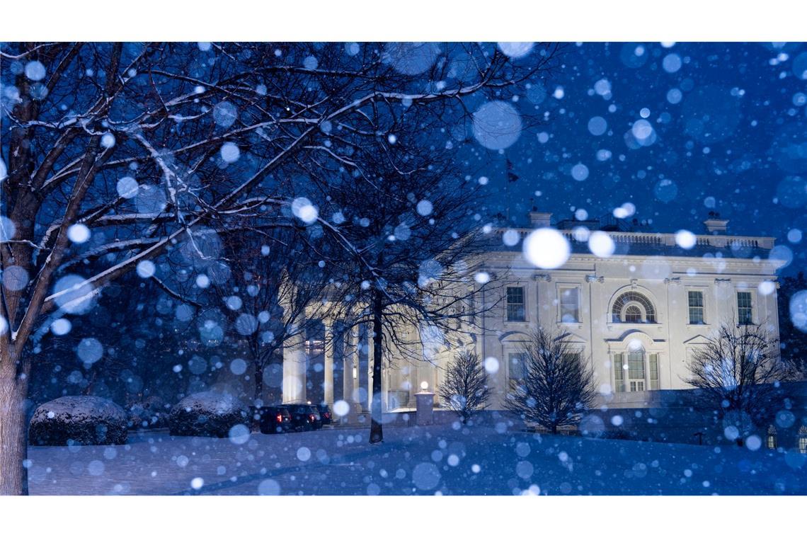 Schnee fällt auf das beleuchtete Weiße Haus in Washington.