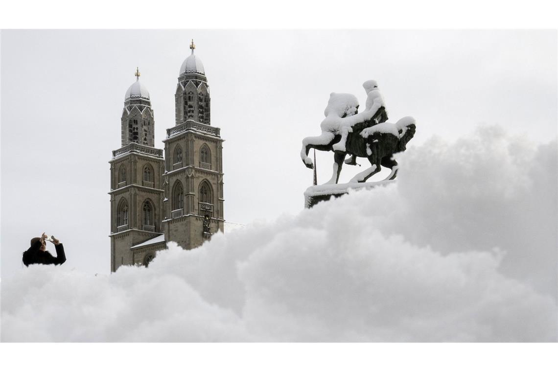 Schnee in der Schweiz: Ein Mann fotografiert das Großmünster in Zürich.