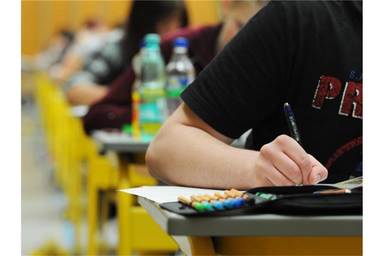 Schüler sitzen in Tischreihen hintereinander und schreiben. Foto: Armin Weigel/Archivbild