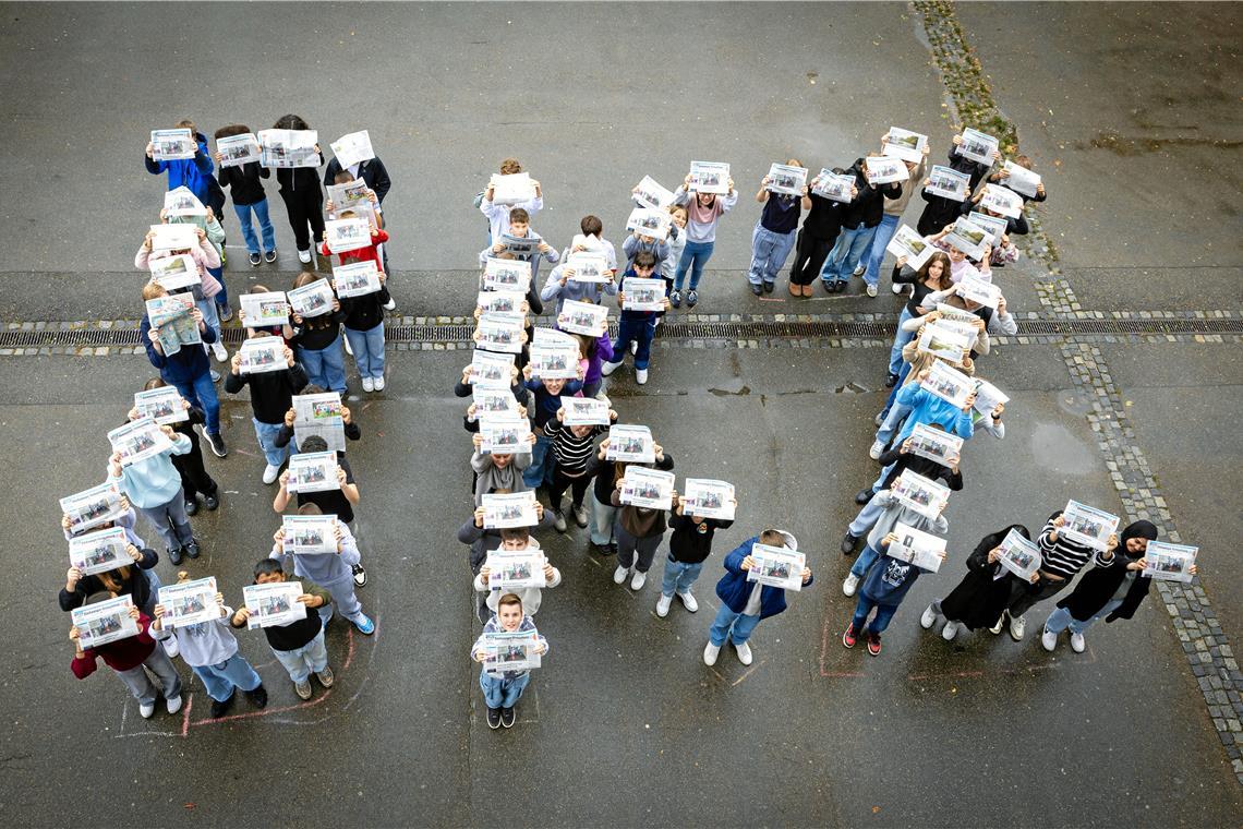 Schülerinnen und Schüler der 8. Jahrgangsstufe an der Max-Eyth-Realschule erhalten am ersten Projekttag ihre Zeitungen. Damit werden sie direkt kreativ und stellen sich im Schulhof zu einem großen „BKZ“ auf. Foto: Alexander Becher