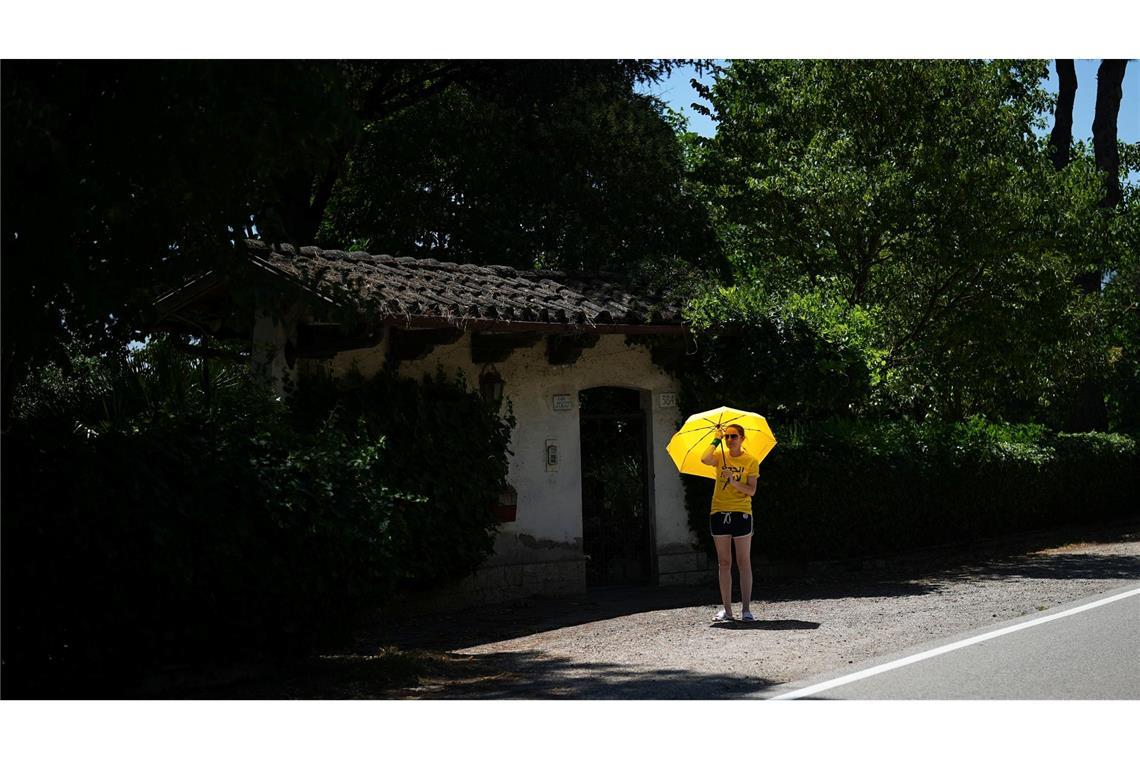 Schwitzen am Wegesrand: Unter einem Schirm wartet eine Zuschauerin auf die Teilnehmer der Tour de France in Italien. Bei Temperaturen bis zu 36 Grad legen die Radfahrer die Strecke von Cesenatico bis Bologna zurück.