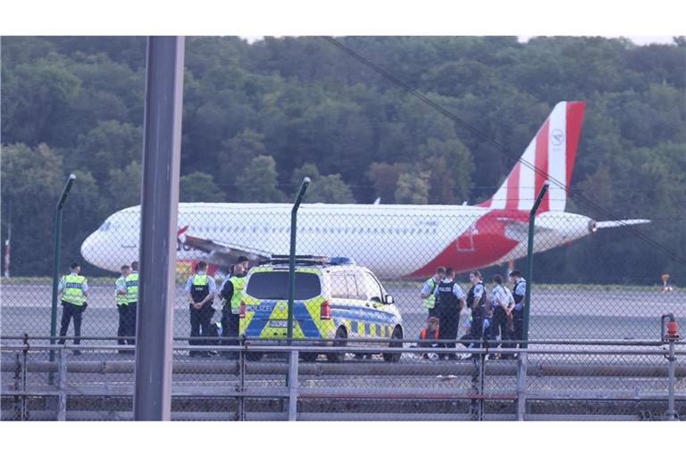 Sicherheitspersonal und Polizisten stehen im Juli 2023 auf dem Flugfeld und versuchen Aktivisten der Gruppe Letzte Generation vom Asphalt zu lösen, nachdem sie sich festgeklebt haben.