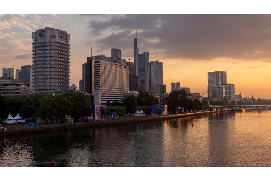 Sonnenaufgang hinter der Frankfurter  Skyline - im Vordergrund das Ufer des Mains.