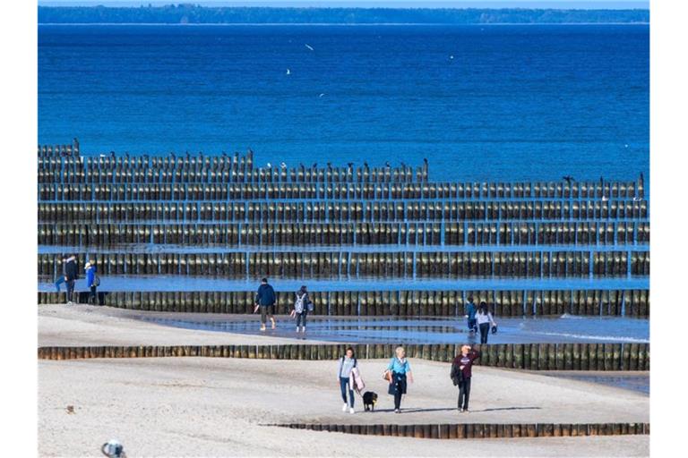 Spaziergänger am Strand von Koserow auf der Ostseeinsel Usedom. Foto: Jens Büttner/dpa-Zentralbild/dpa