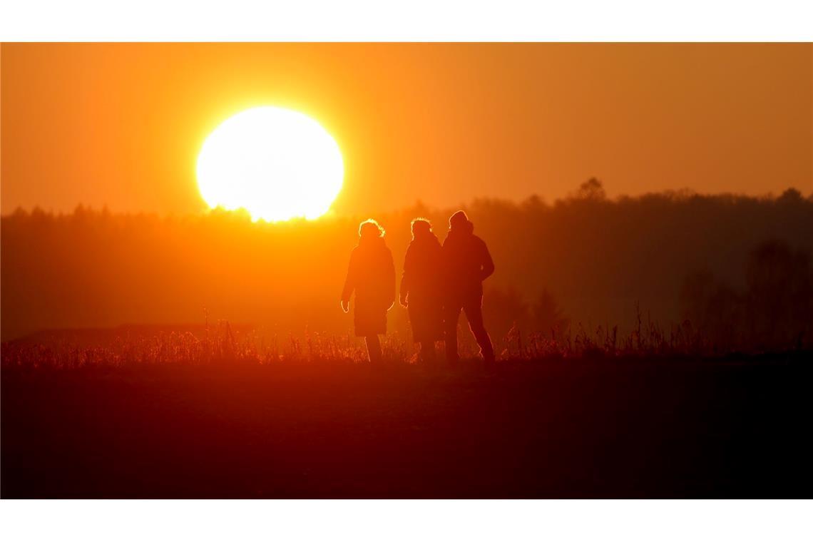 Spaziergang an Weihnachten: Menschen gehen im Licht der untergehenden Sonne bei Altheim in Baden-Württemberg durch die Landschaft.