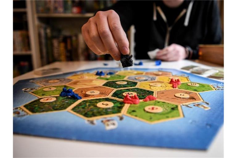 Spieler spielen das Spiel „Siedler von Catan“. Foto: Britta Pedersen/dpa-Zentralbild/dpa/Archivbild