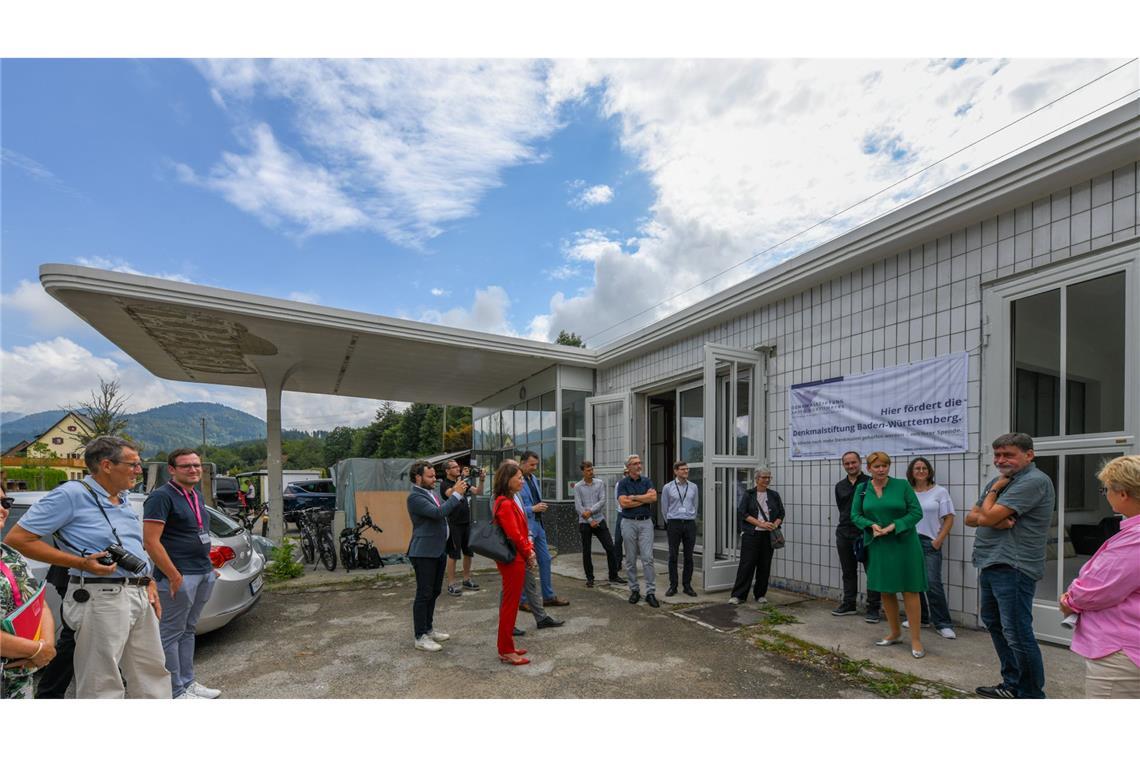 Staatssekretärin Andrea Lindlohr (im grünen Kleid) besuchte die zum Wohnhaus umgenutzte Tankstelle in Kirchzarten im Südschwarzwald aus den 1950er Jahren. Durch das hohe Engagement der Eigentümer bleibt die Tankstelle als Zeitzeugnis der Nachkriegsmoderne erhalten. Die Tankstelle veranschaulicht,  wie sich die ländlichen Regionen um Freiburg in der Nachkriegszeit durch den aufkommenden Tourismus und Autoverkehr veränderten. Die Umnutzung der Tankstelle in ein Wohnhaus zeigt, dass historischen Bauwerken durch innovative Nutzungskonzepte viele Möglichkeiten offenstehen.