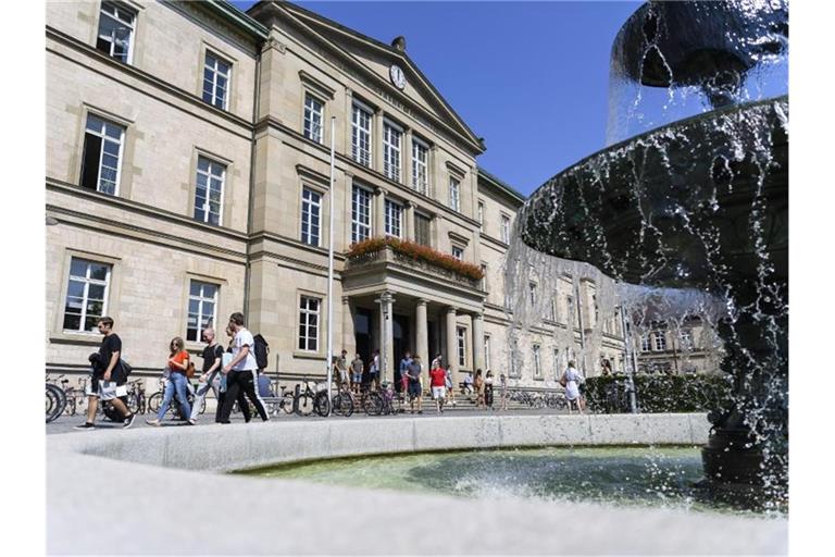Studentinnen und Studenten laufen vor der Universität Tübingen an einem Brunnen vorbei. Foto: Edith Geuppert/dpa/archivbild