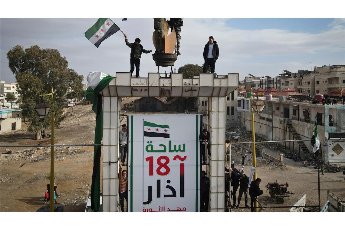 Syrer schwenken nach dem Freitagsgebet während einer Demonstration in Daraa Fahnen, um den Sturz der Regierung von Assad zu feiern.