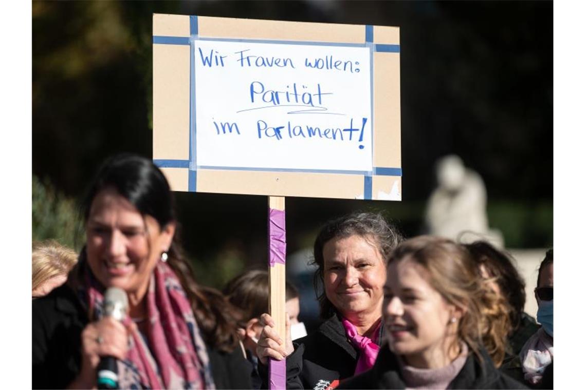 Teilnehmerinnen einer Kundgebung stehen neben einem Plakat mit der Aufschrift „Wir Frauen wollen Parität im Parlament!“. Foto: Marijan Murat/dpa